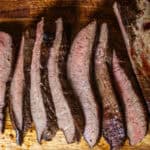 Thinly sliced beef heart on a wooden cutting board.