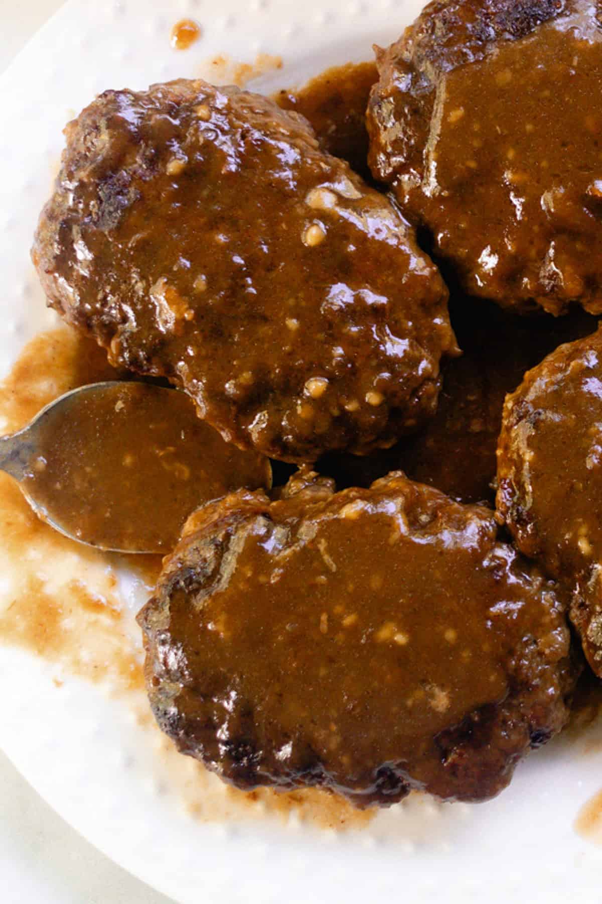 French onion soup on a white plate with salisbury steak on top.