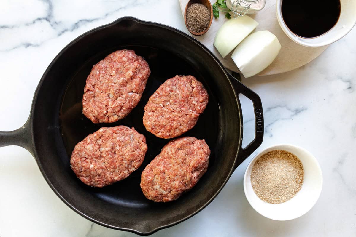 Searing 4 salisbury steak patties in a cast iron skillet. 