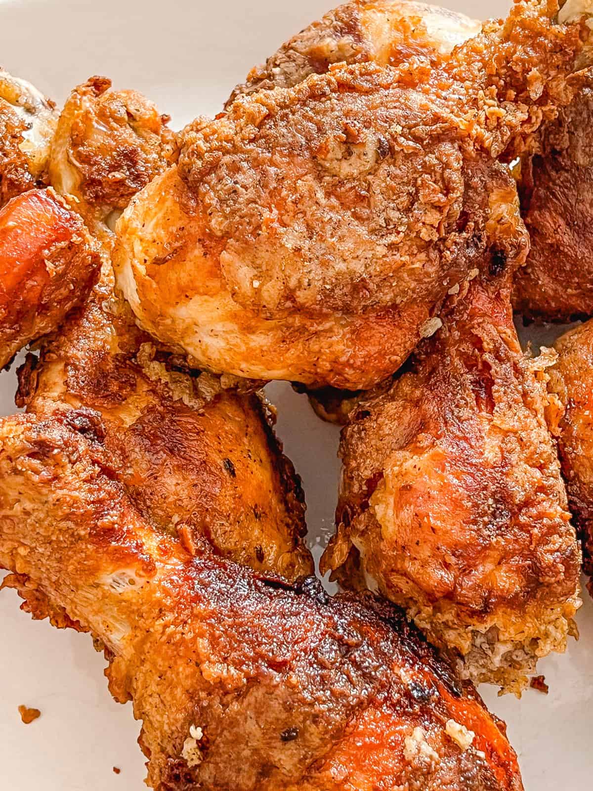 Several pieces of fried chicken on a white plate.