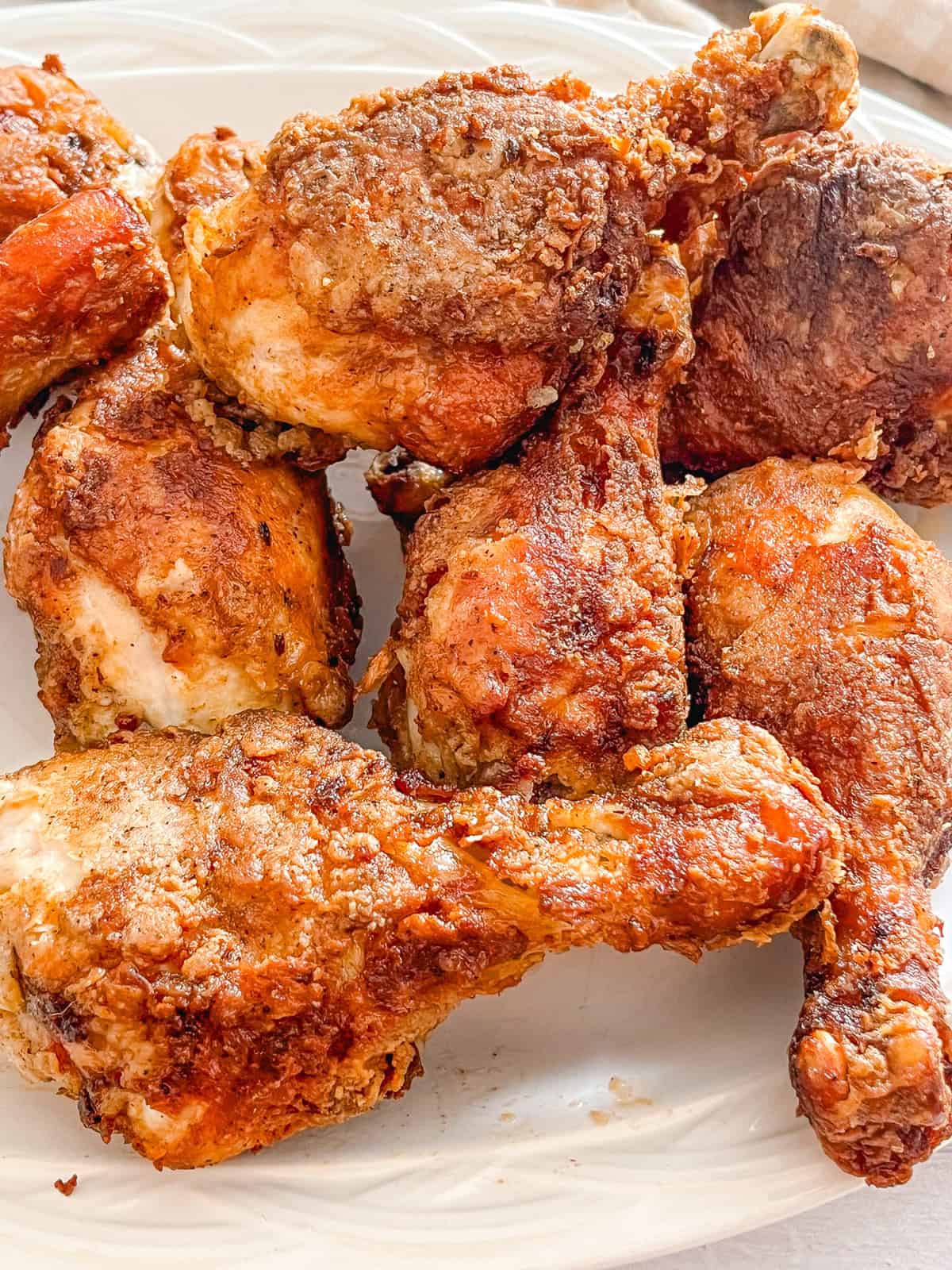 Very crispy pieces of chicken piled high on a white plate. 