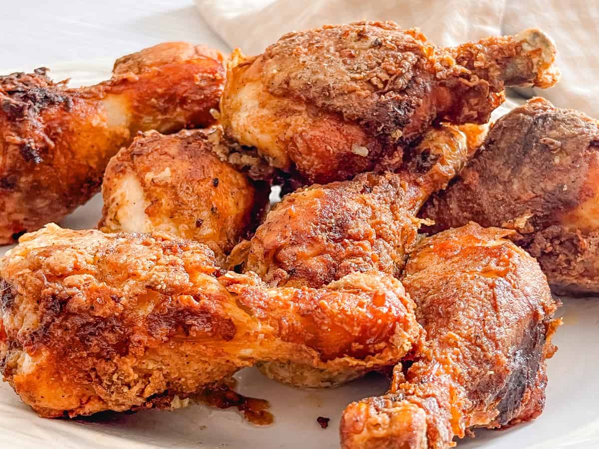 Fresh Cast Iron Buttermilk Fried Chicken drumsticks on a white plate.