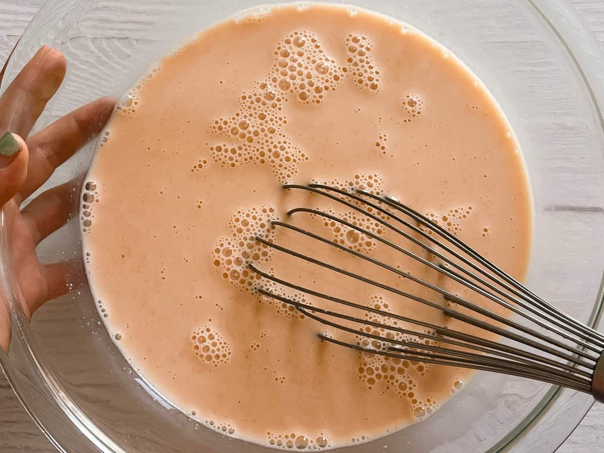 Buttermilk and hot sauce mixture in a bowl with a whisk.