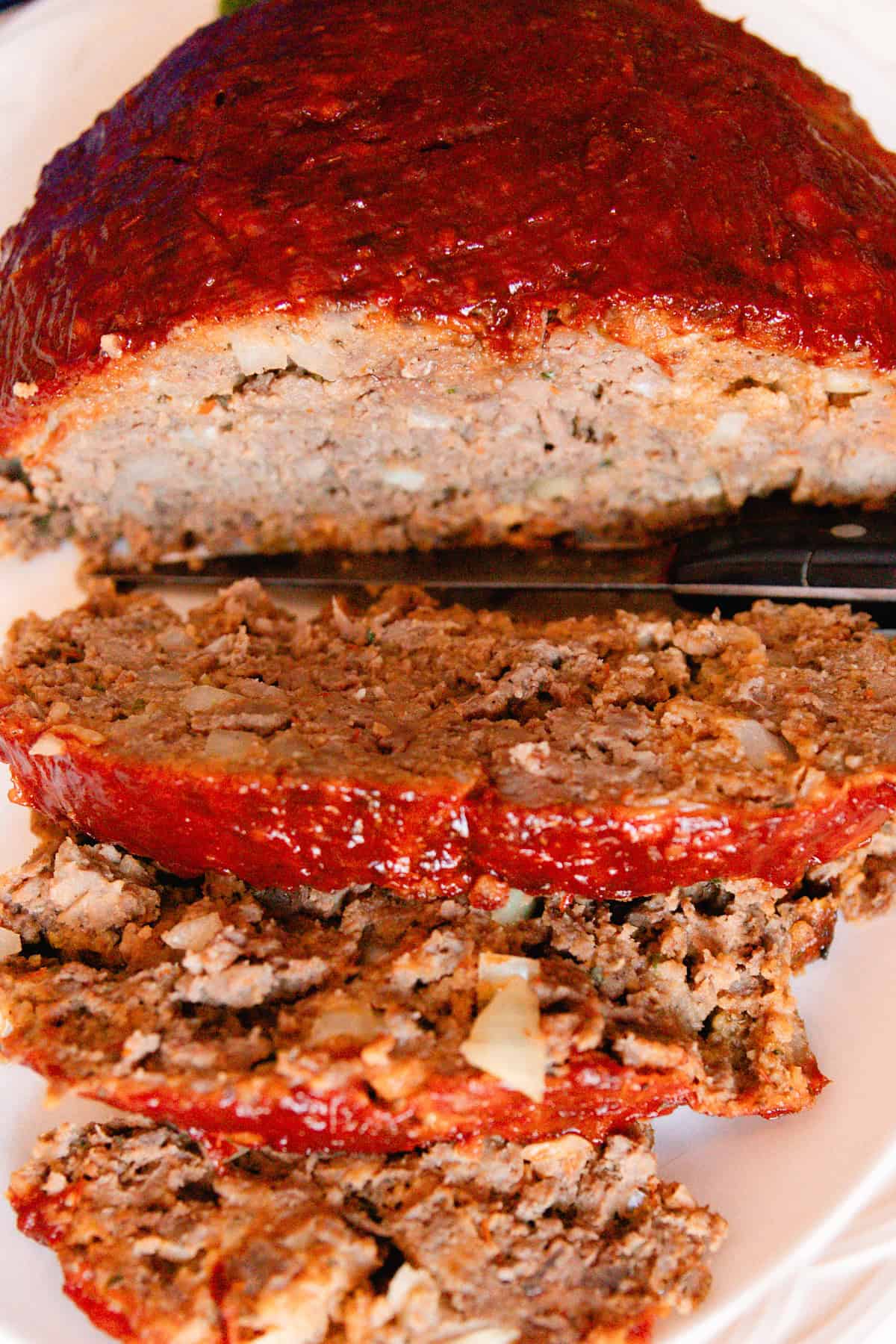 Dutch oven meatloaf with a chili sauce glaze and several slices cut out of it.