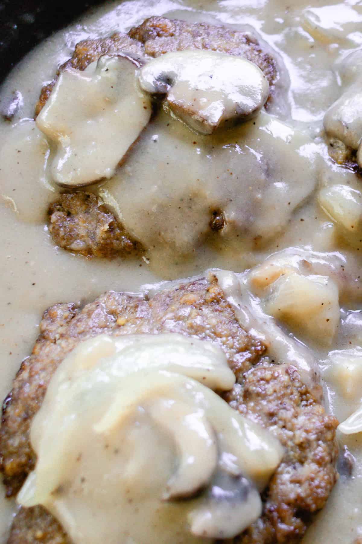 Gravy smothered hamburger steak in a cast iron pan.