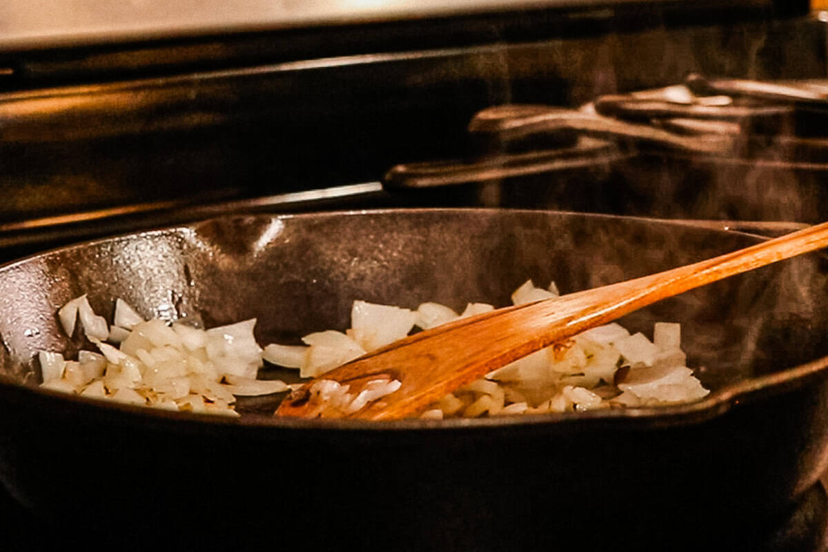 Onions being cooked down in a cast iron skillet.