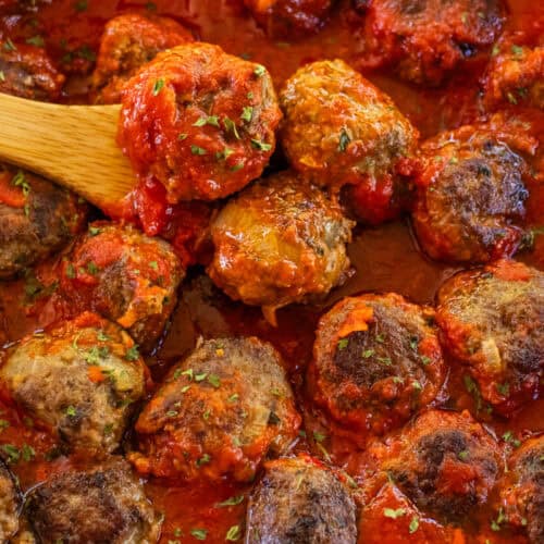 Homemade Stovetop Meatballs bathed in a thick red sauce in a cast iron skillet.
