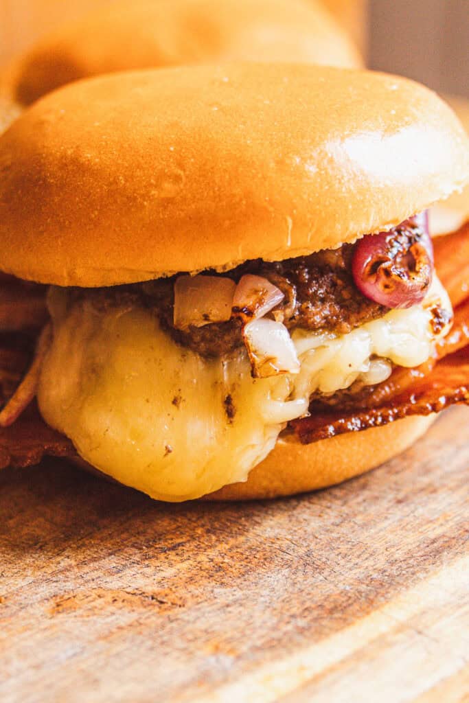 A cheese stuffed burger with bacon and onions on a bun.