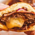 A cheese stuffed burger with a bite taken out of it.