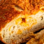 Artisan cheese bread cooling on a wooden cutting board.