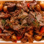 Shredded slow cooker venison roast in a white serving dish.