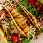 Venison Tacos on a white plate with a sauce drizzle on top.
