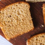 Whole wheat freshly milled sandwich bread with several slices cut, on a wooden cutting board.