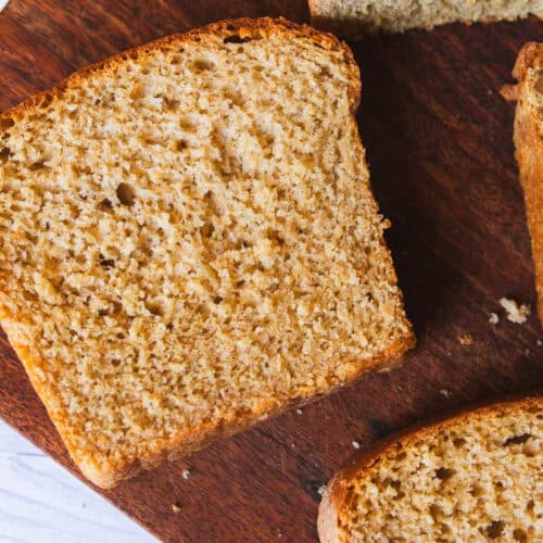 Whole wheat freshly milled sandwich bread with several slices cut, on a wooden cutting board.