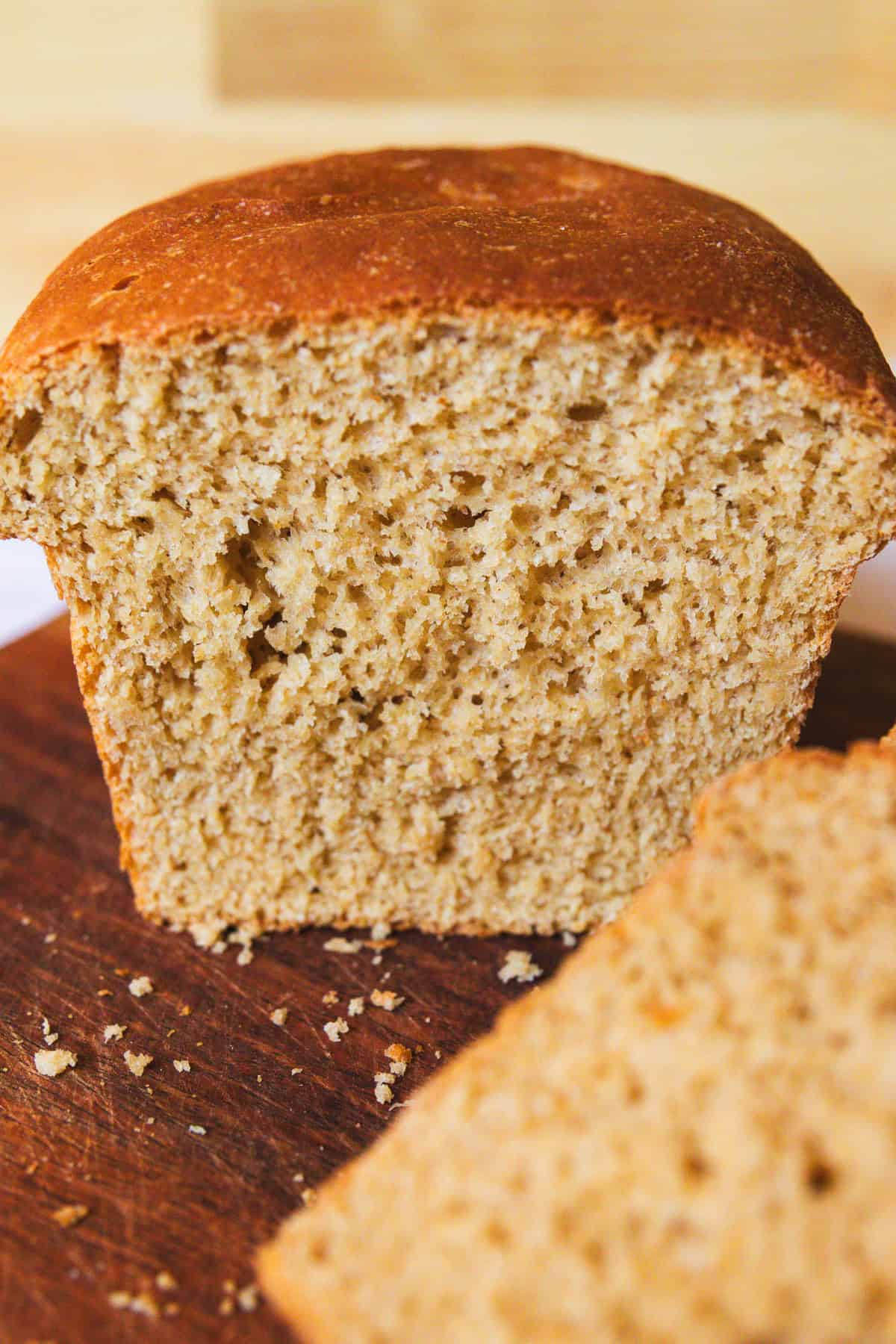 Half of a loaf of whole grain bread on a wooden cutting board.