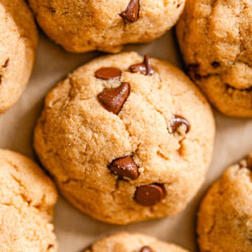 Whole grain chocolate chip cookies lined up on parchment paper.