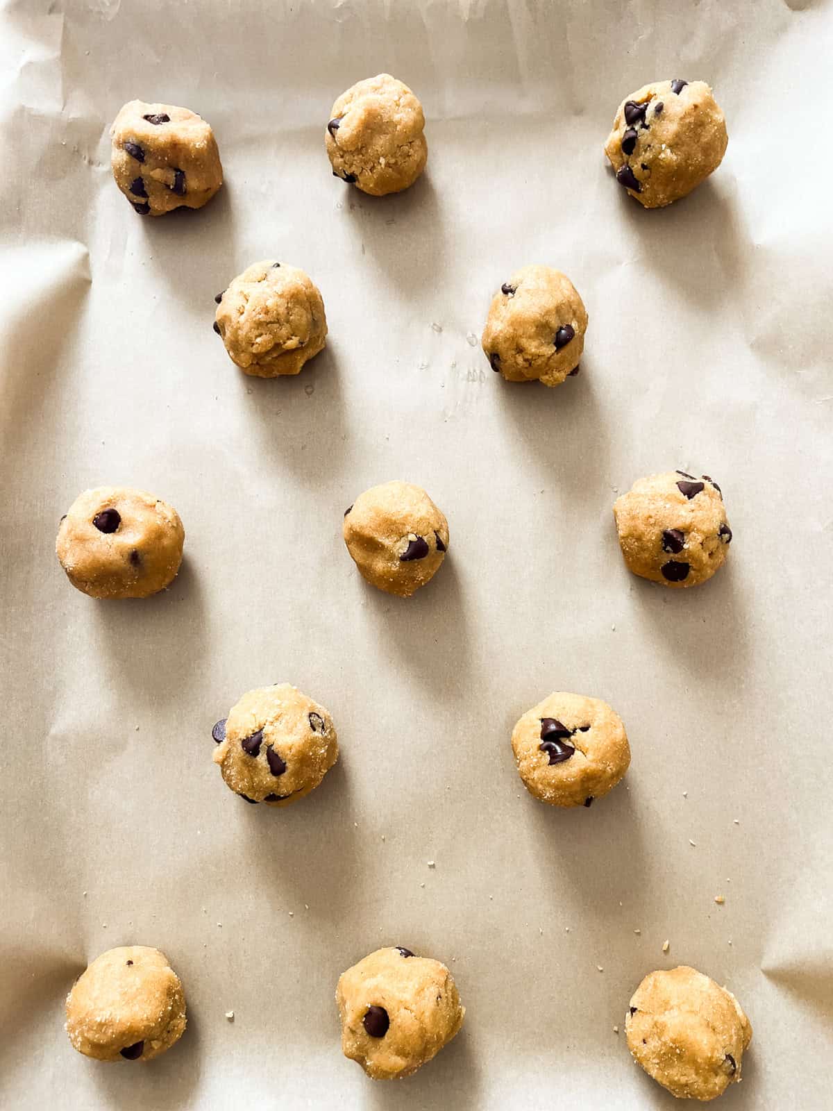 Chocolate chip cookie dough balls on a baking sheet.