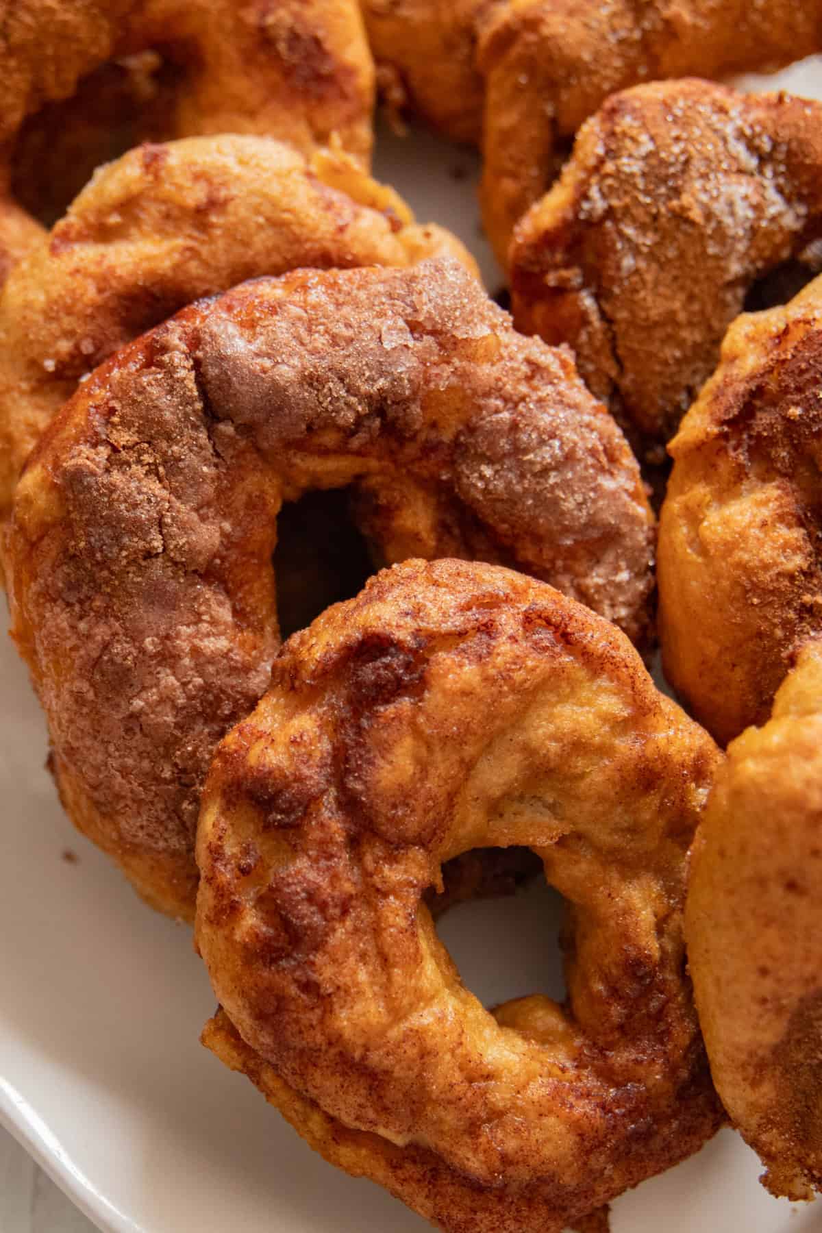 Cinnamon sugar bagels stacked on a white plate.