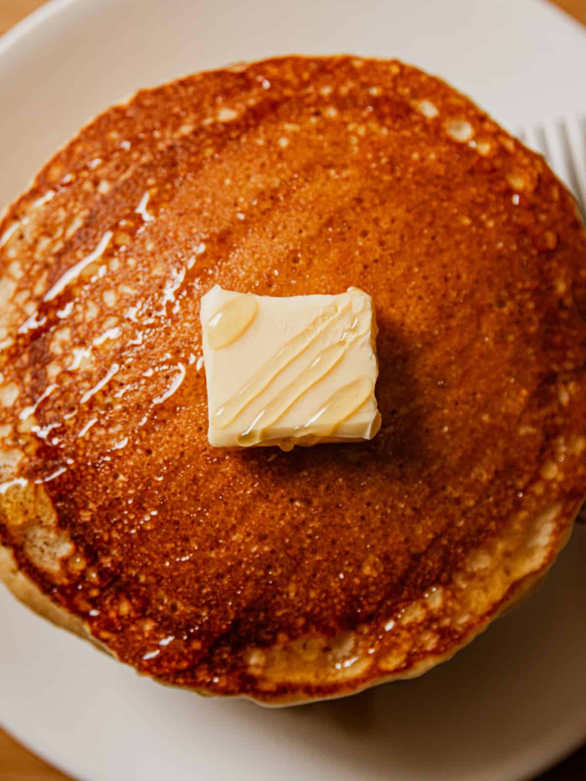 A plate of pancakes with a pat of butter on top.