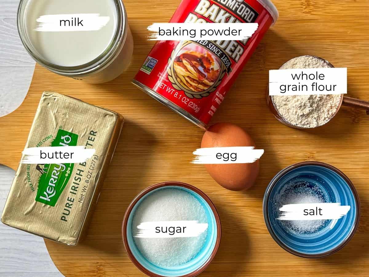 Whole grain pancake ingredients assembled on a wooden cutting board.