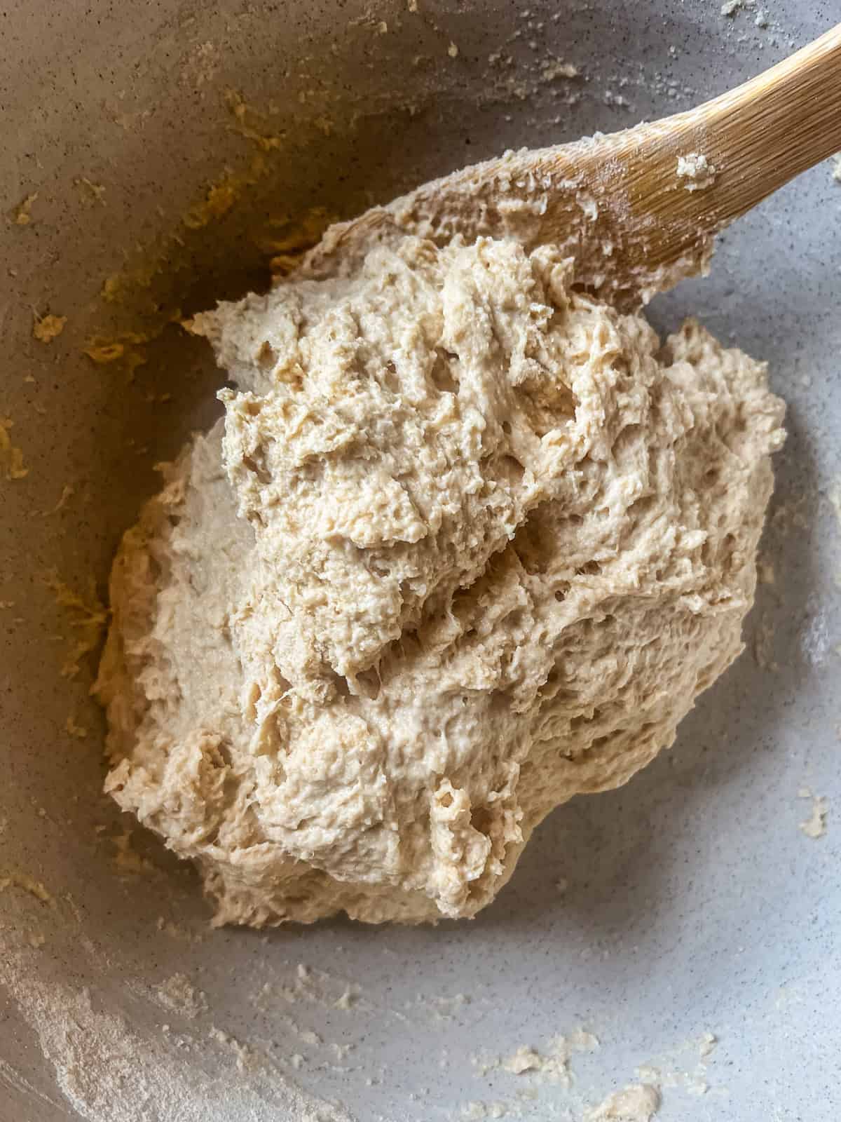 Stirring a shaggy dough with a wooden spoon.