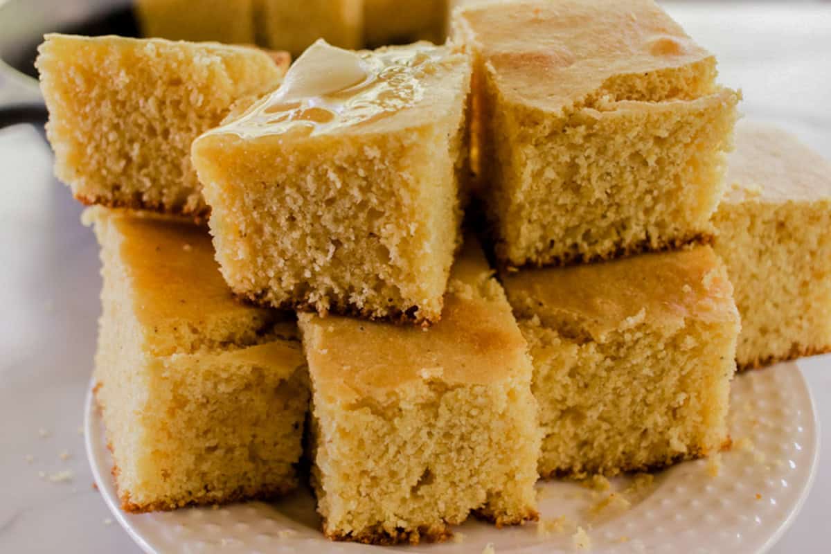A pile of Cast Iron Cornbread squares on a white plate.