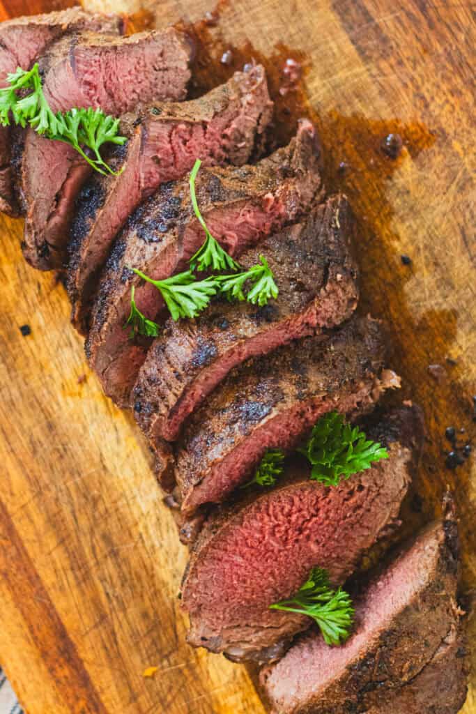 Venison Backstrap sliced and plated up on a cutting board.
