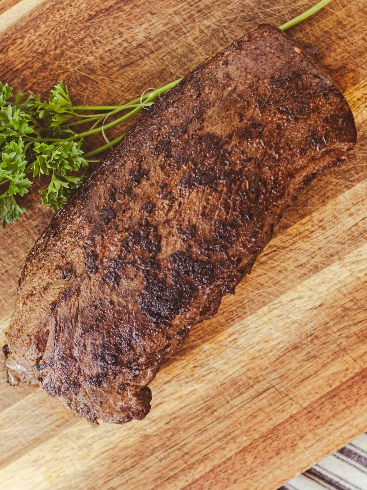 Resting the meat on a wooden cutting board before slicing it. 