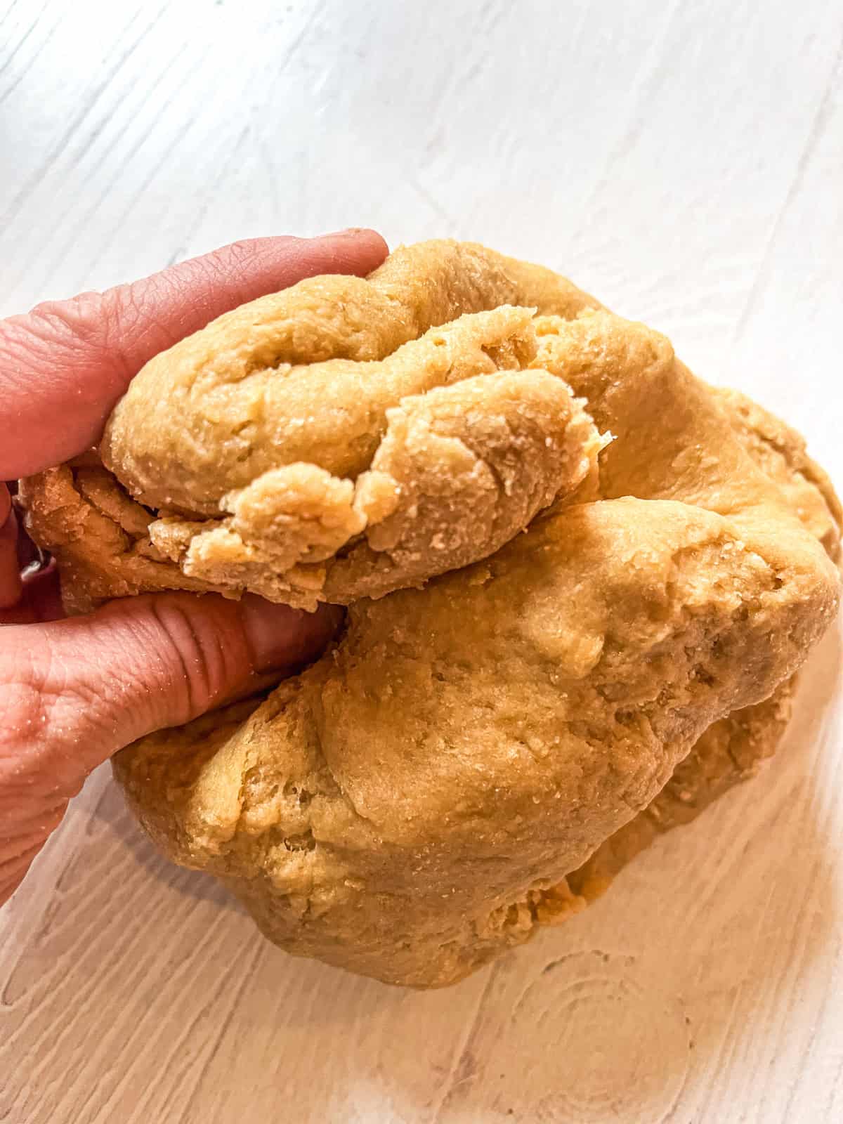Kneading cinnamon roll dough on a white table.