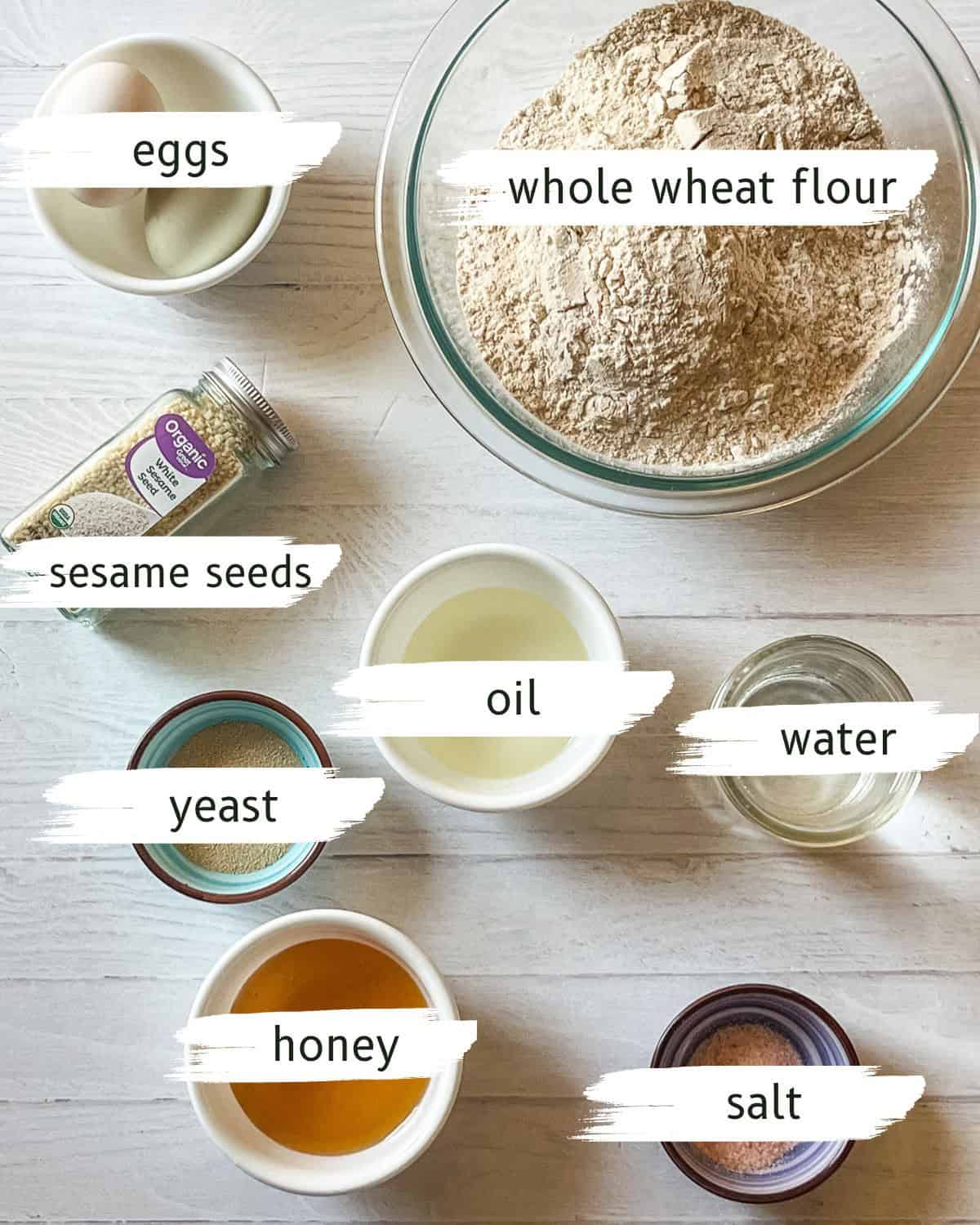 Whole grain hamburger bun ingredients assembled and labeled on a white table.
