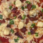 A fresh milled flour pizza dough topped with cheese, meat, and veggies.