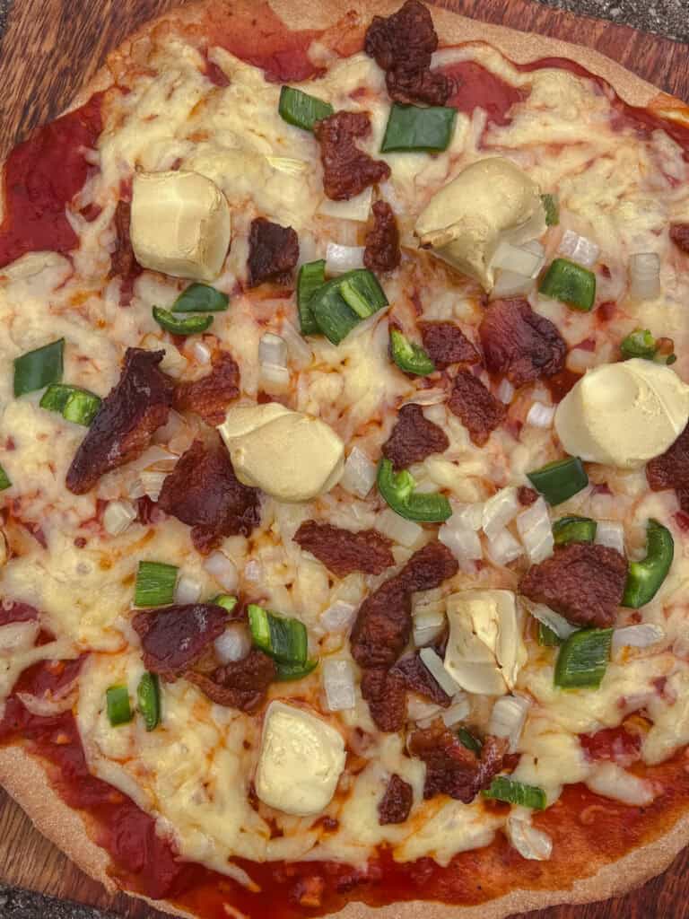 A pizza topped with cheese, meat, and veggies, made with whole grain pizza dough.