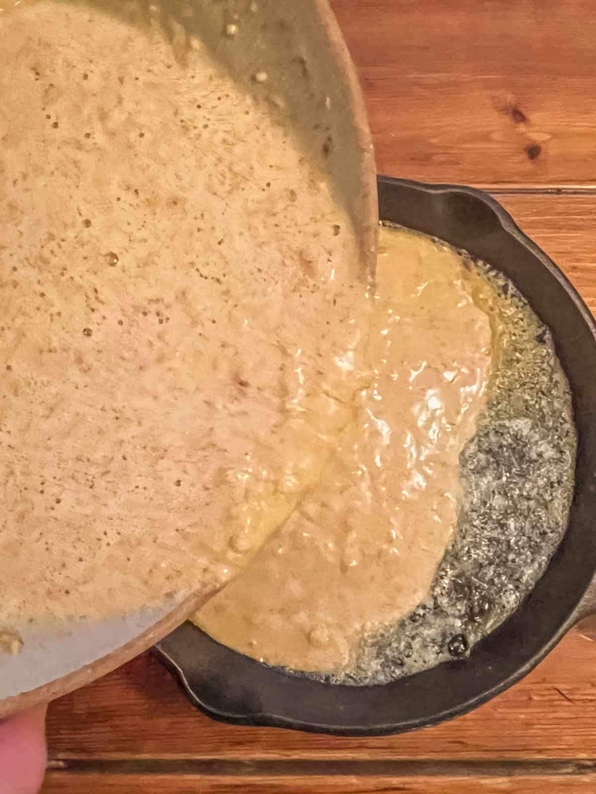 Pouring puff pancake batter into a cast iron skillet.