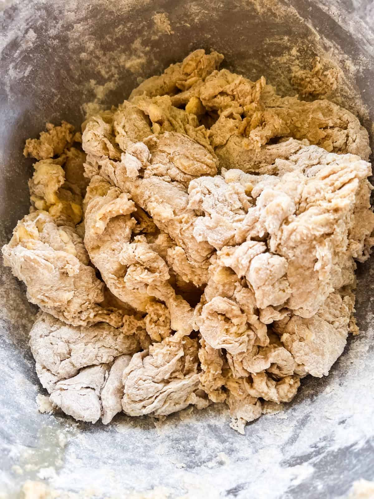 A shaggy ball of biscuit dough in a metal mixing bowl.