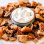 Fried trout pieces on a plate surrounding a cup of dip.
