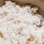 A bowl of cooked white rice and a serving spoon.