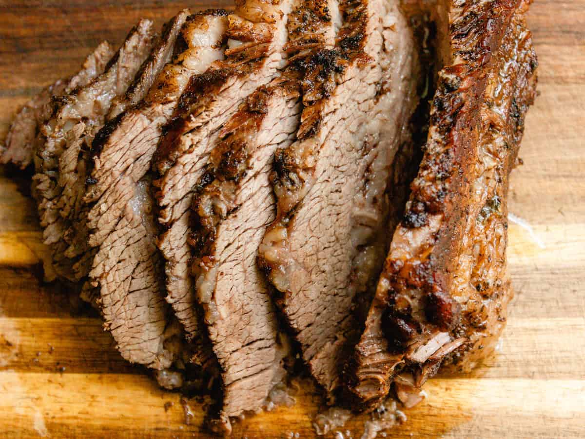 Sliced braised brisket on a wooden cutting board.