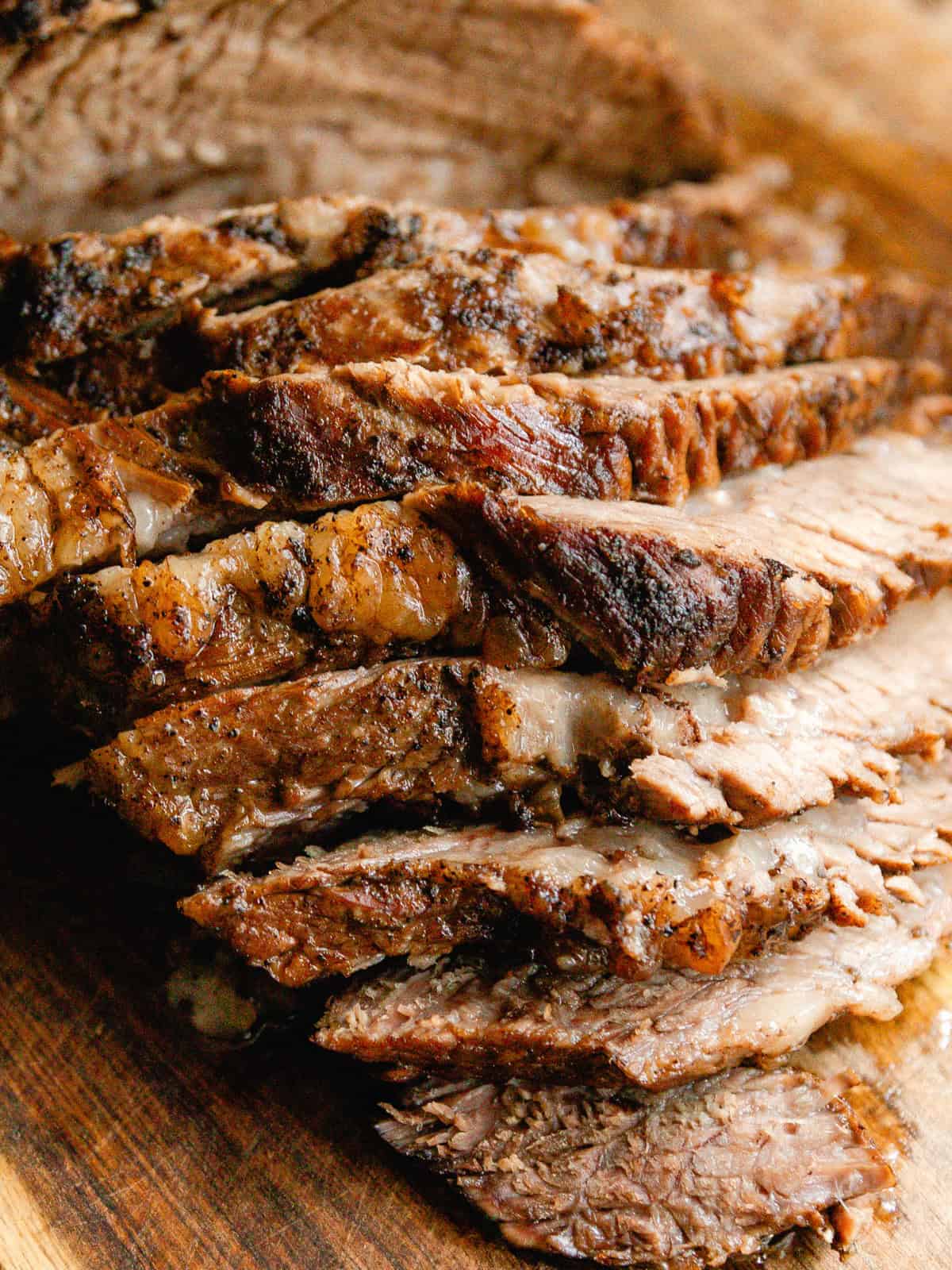 Braised brisket sliced thick on a wooden cutting board.