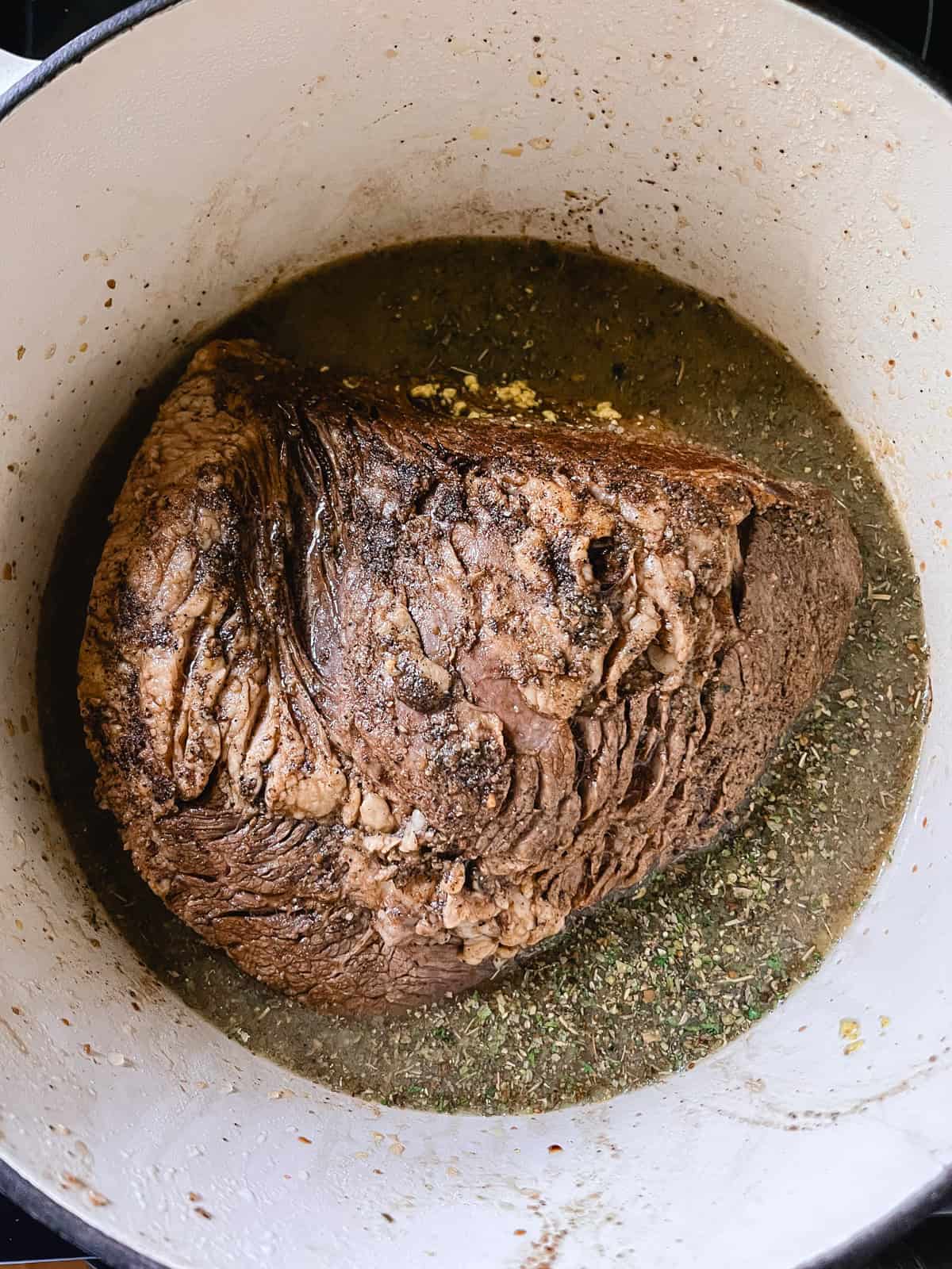 Seared brisket in a dutch over, in a pool of braising liquid.