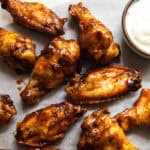 Baked chicken sings on a plate with a cup of ranch dressing.