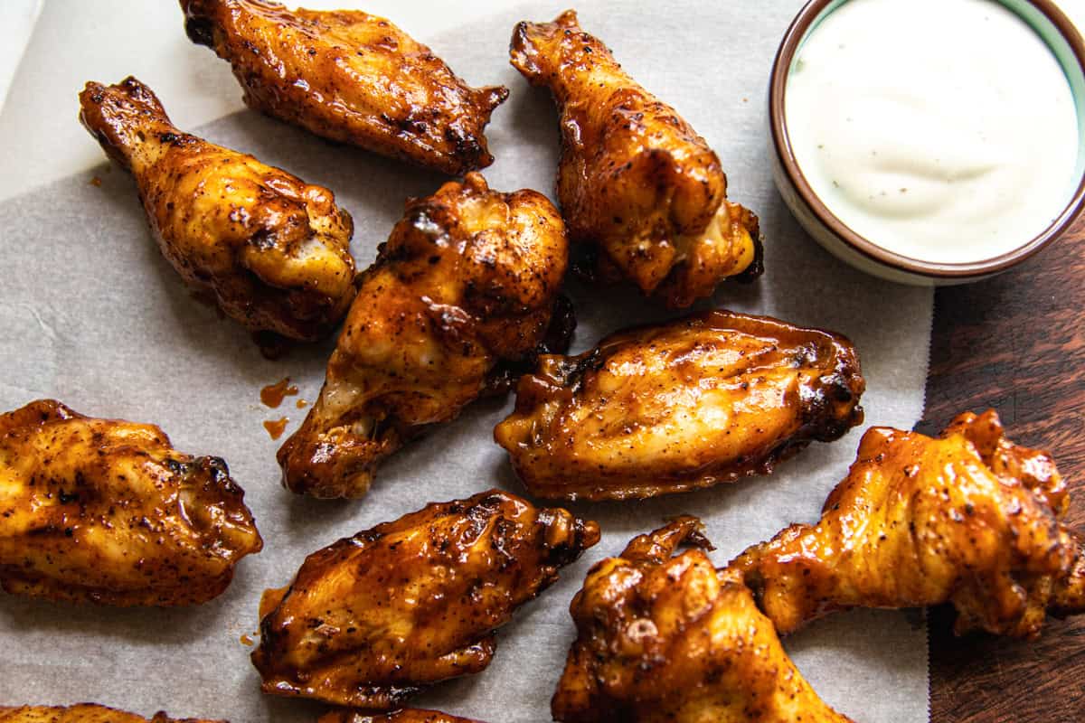 Baked chicken sings on a plate with a cup of ranch dressing.