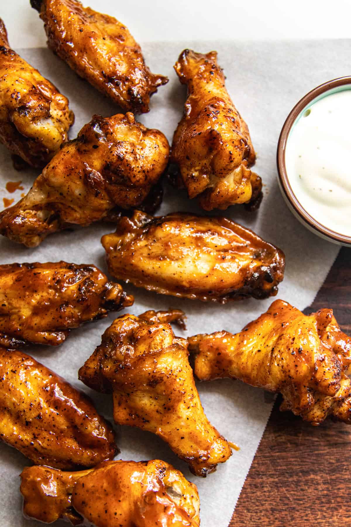Homemade chicken wings on parchment paper with a cup of ranch.