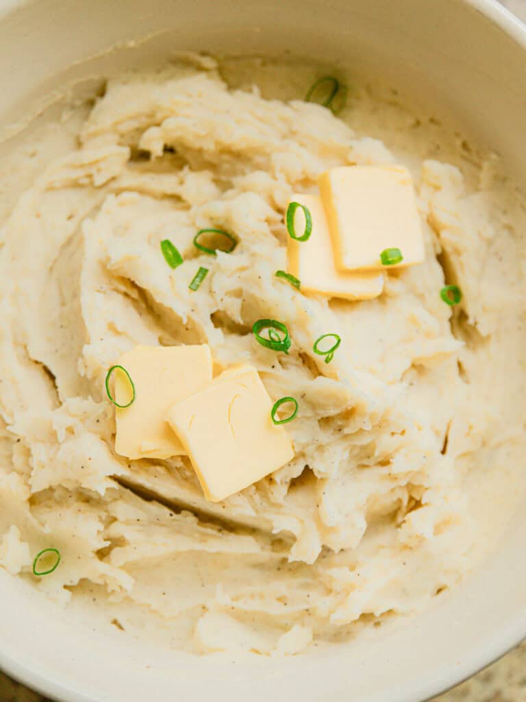 Mashed potatoes with butter and chives on top.