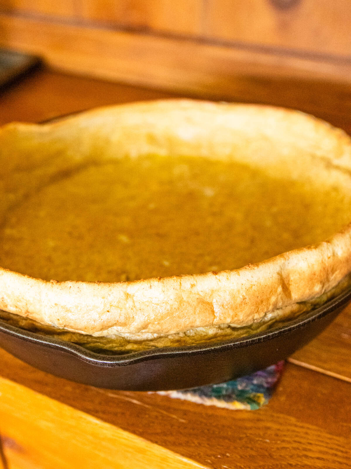 A fresh dutch baby pancake rising up out of a cast iron skillet.