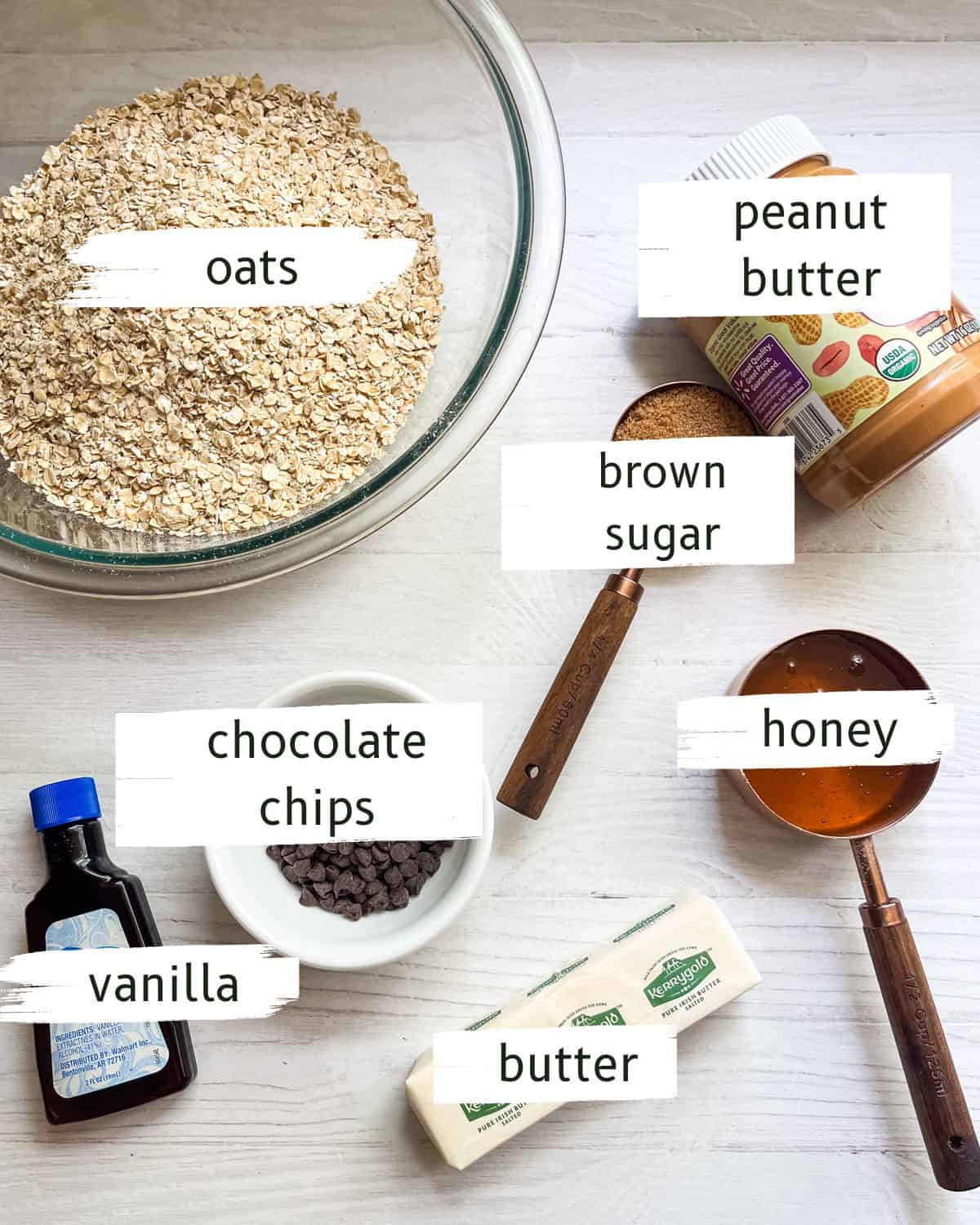 Homemade granola bar ingredients labeled on a white table. 
