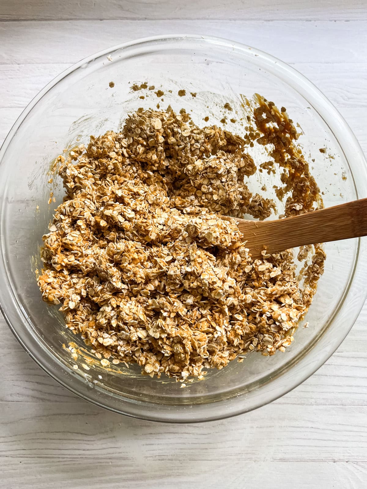 Mixing homemade granola bar ingredients together in a glass bowl.