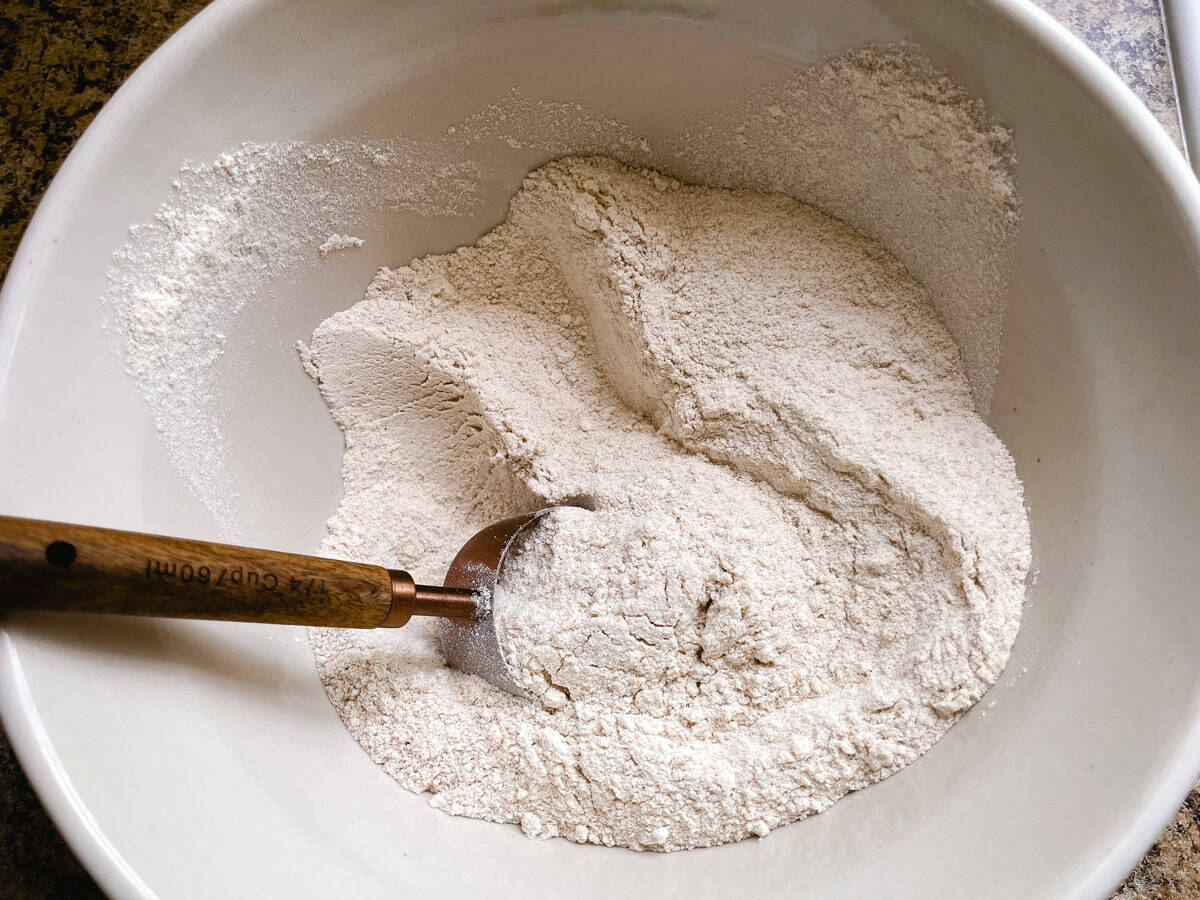 Freshly milled flour in a bowl with a measuring cup.