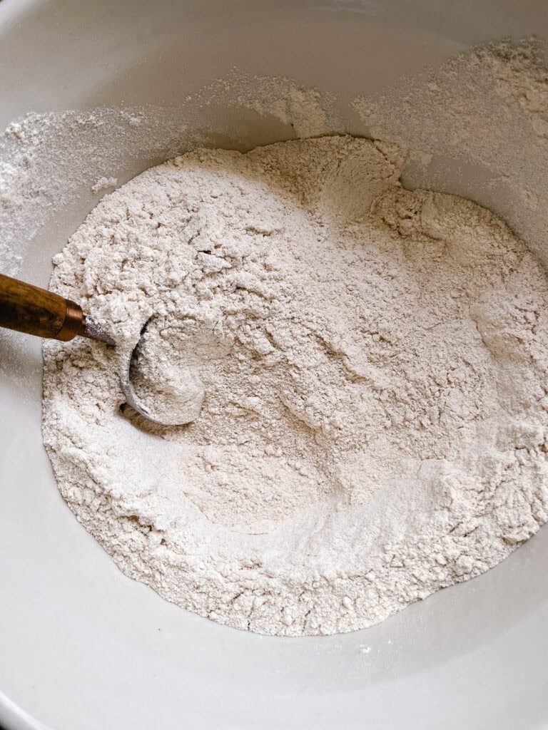 A bowl of freshly milled flour with a measuring spoon in it.