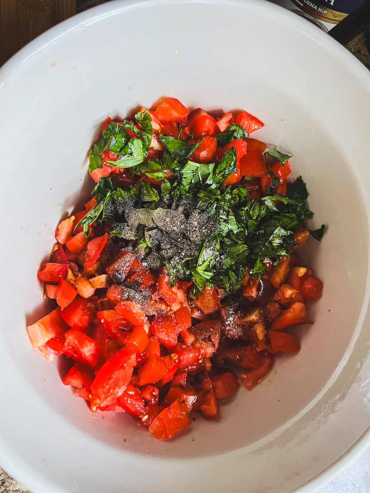 Chopped tomatoes and other bruschetta ingredients in a bowl.
