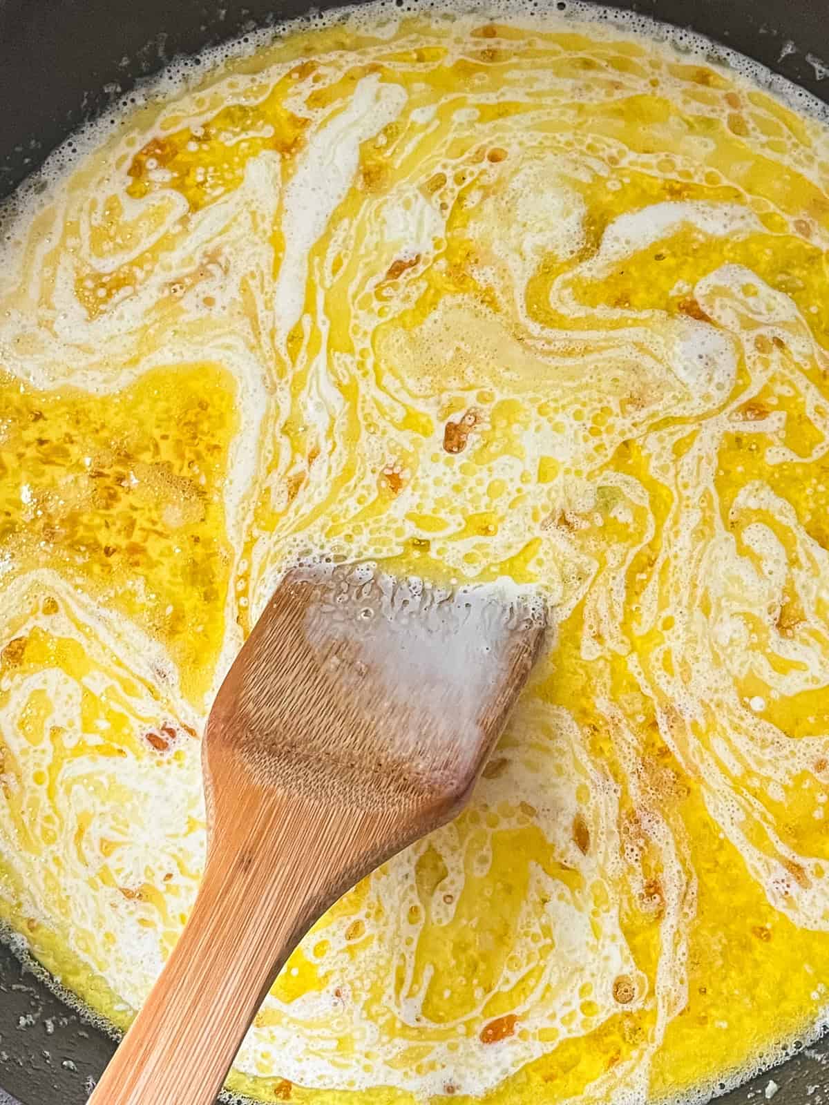 Stirring alfredo sauce in a cast iron skillet.